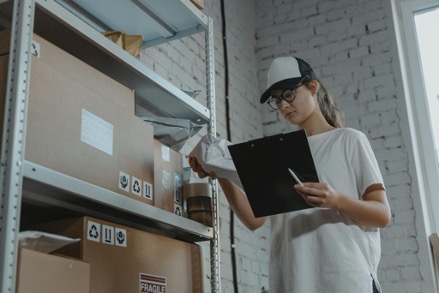 A woman holding a clipboard checks inventory in a warehouse office – Slotted